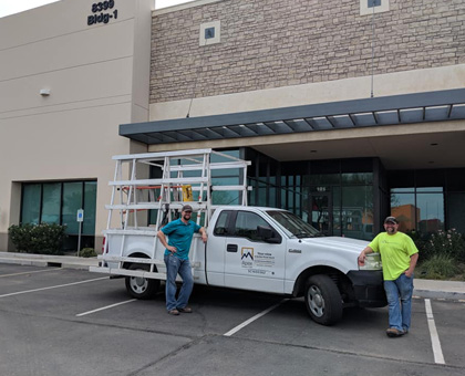 two apex windows employees leaning on work truck